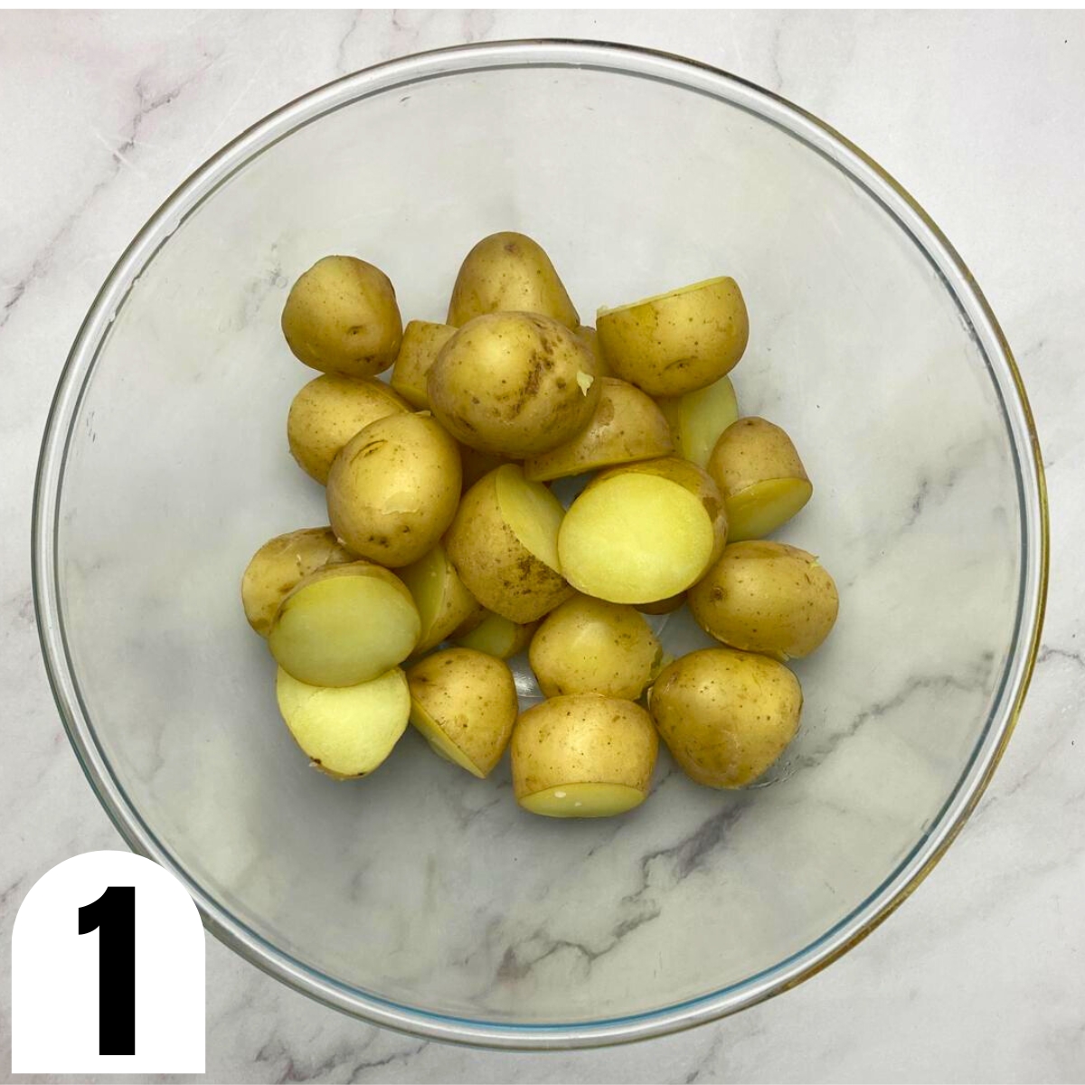 Glass bowl with boiled baby potatoes in it.